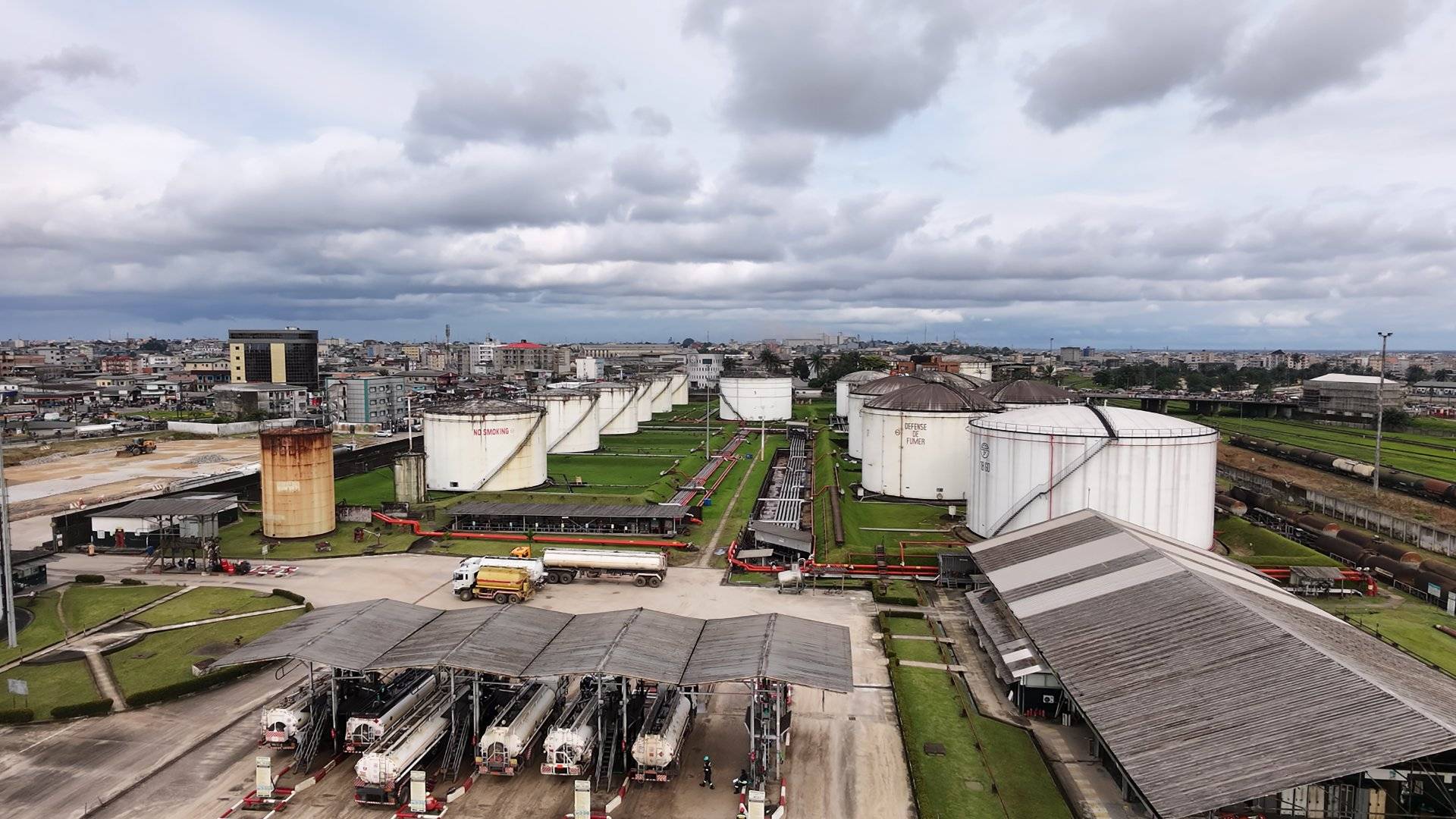 Vue aérienne du dépôt de Bessengue de la SCDP avec camions-citernes et la ville de Douala en arrière-plan